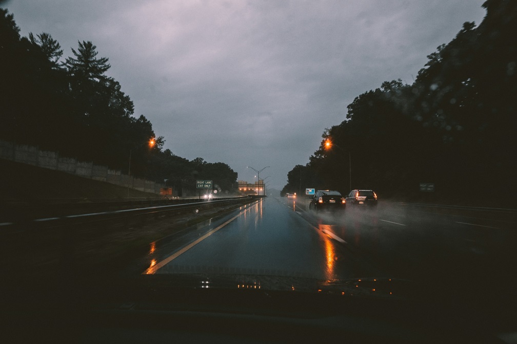 Coche conduciendo de noche en una autopista mientras llueve. 